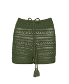 Green crochet shorts against a white wall.