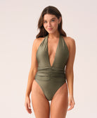 Woman wearing a green one piece swimsuit against a white background