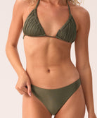 Woman wearing a green bikini with macrame details on a plain background