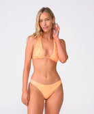 A woman wearing an orange bikini standing against a white wall.