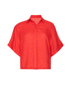 A red short sleeve linen top against a white wall. 