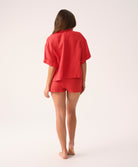 Woman wearing a red shirt and short set on a white background