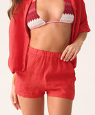 Woman wearing a red bikini set with a red shirt and short set on a white background