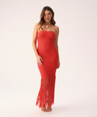 Woman wearing a red strapless dress with fringe on a white background