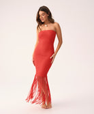 Woman wearing a red strapless dress with fringe on a white background