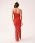 Woman wearing a red strapless dress with fringe details on a white background