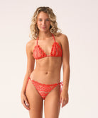 Woman wearing a red bikini with intricate lace details on a white background