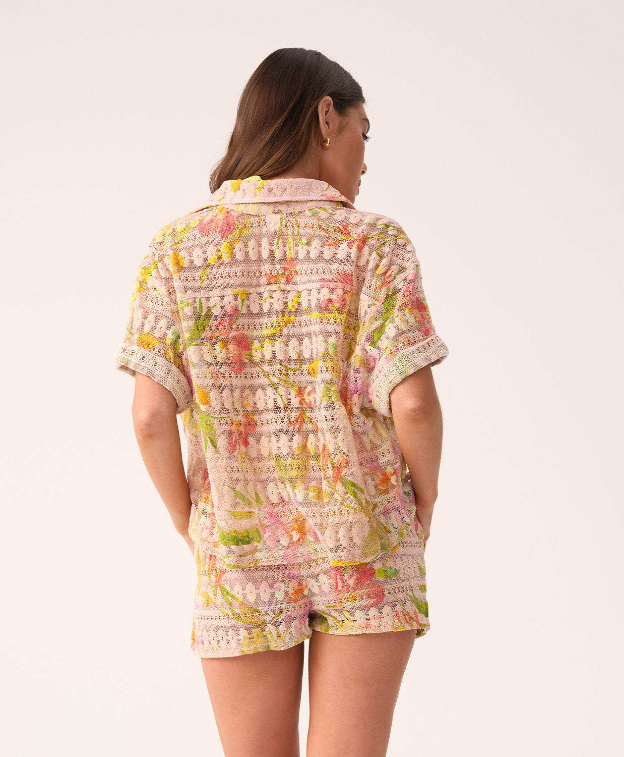 Woman wearing a colorful patterned shirt and shorts on a white background