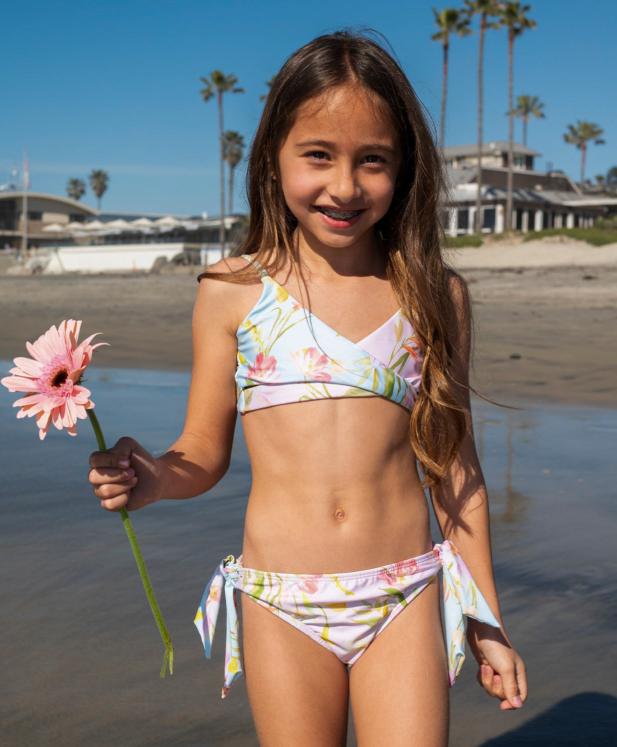 Kids Petal Gianna Bikini – light blue floral two-piece with crisscross top and oversized tie bottoms, perfect for sunny beach days.