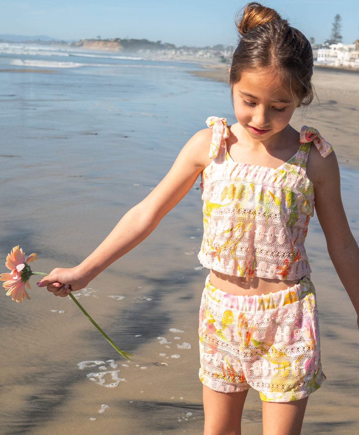 Young girl on a beach holding a flower, wearing a Petal Lainey Lace Set.