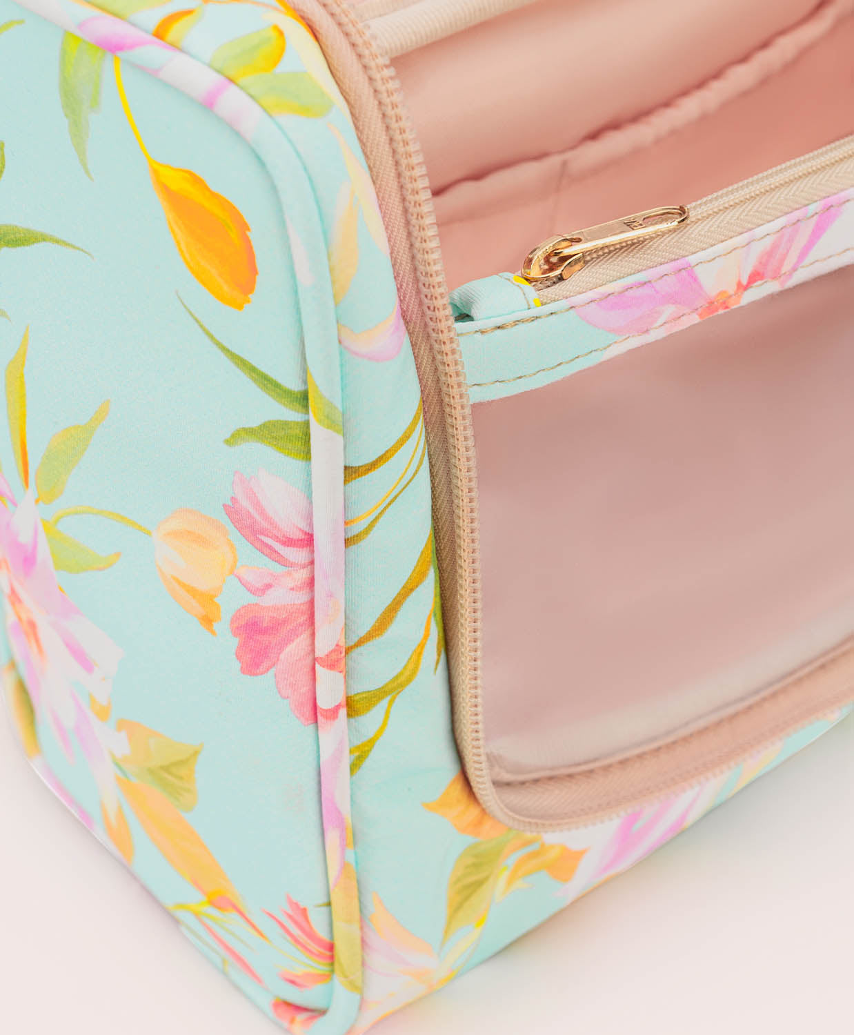 Floral-patterned cosmetic bag with a pink interior on a light background