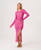 Woman wearing a pink long-sleeve dress with a slit on a white background