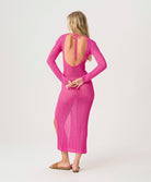 Woman wearing a pink dress with long sleeves and an open back on a white background