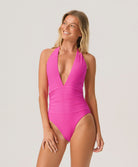 Woman wearing a bright pink swimsuit on a plain background