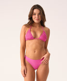Woman wearing a pink bikini against a white background