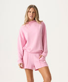 Woman wearing a pink sweatshirt and shorts set on a white background