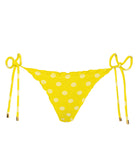 A yellow polka dot bikini against a white wall.