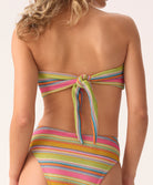 Woman wearing a multicolored striped bikini on a plain background