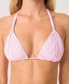 Pink bikini top worn by a woman on a plain background