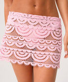 Pink lace mini skirt worn by a woman on a plain background