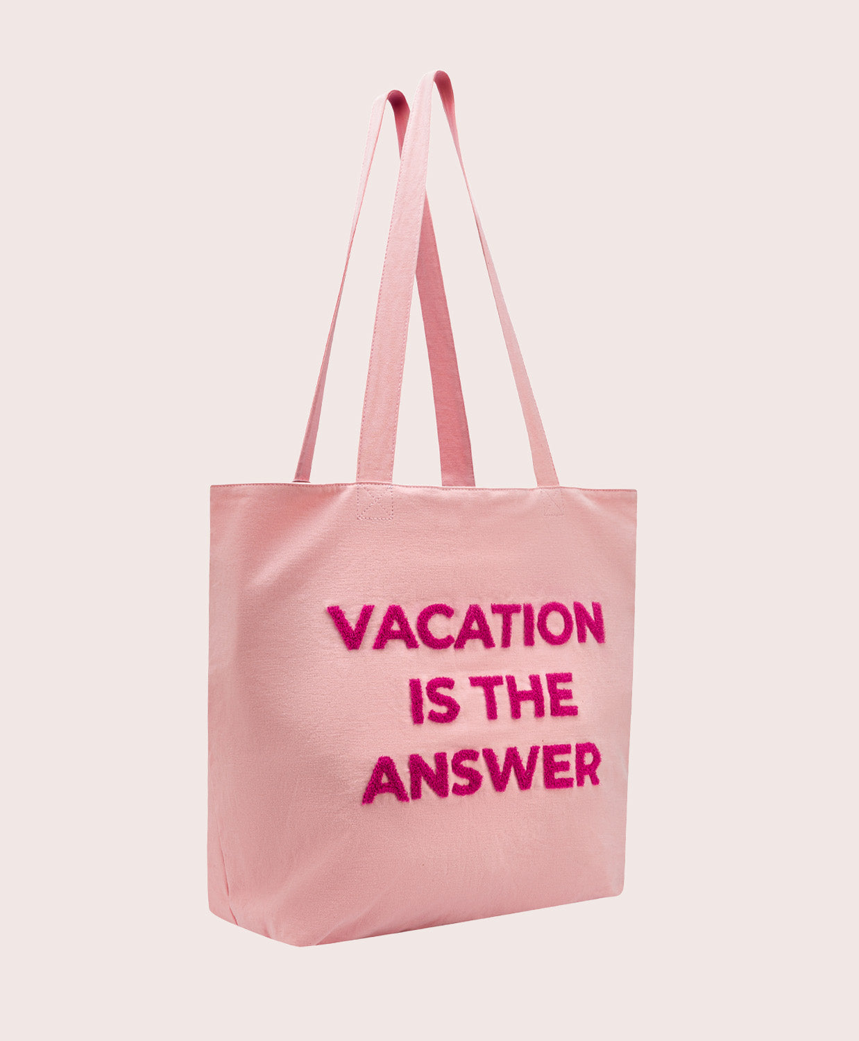 Pink tote bag with 'Vacation is the Answer' text on a light pink background