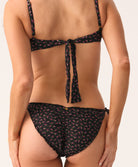 Woman wearing a black floral bikini on a plain background