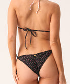 Woman wearing a black patterned bikini on a neutral background