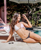 Woman in a bikini sitting by a pool with a garden background