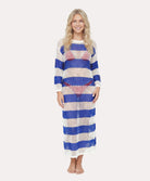 Woman wearing a long, striped dress with blue and white stripes on a plain background
