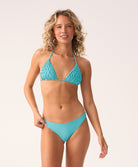 Woman wearing a turquoise bikini against a white background