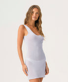 Woman wearing a light gray one-shoulder dress against a white background
