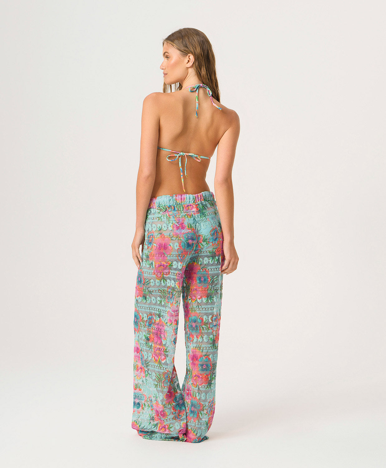 Woman wearing a floral print triangle top and pants on a white background