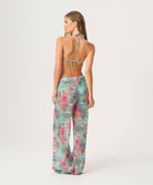 Woman wearing a floral print triangle top and pants on a white background