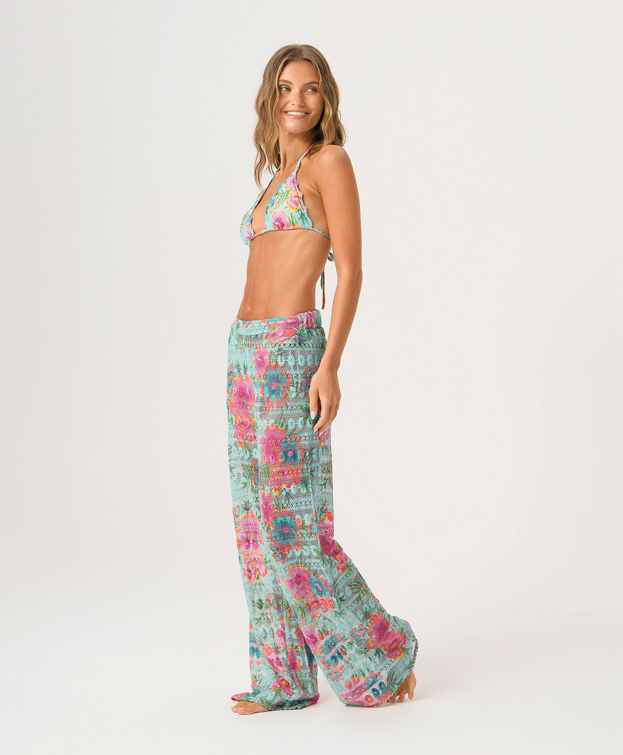 Woman wearing a floral bikini set and matching pants on a white background
