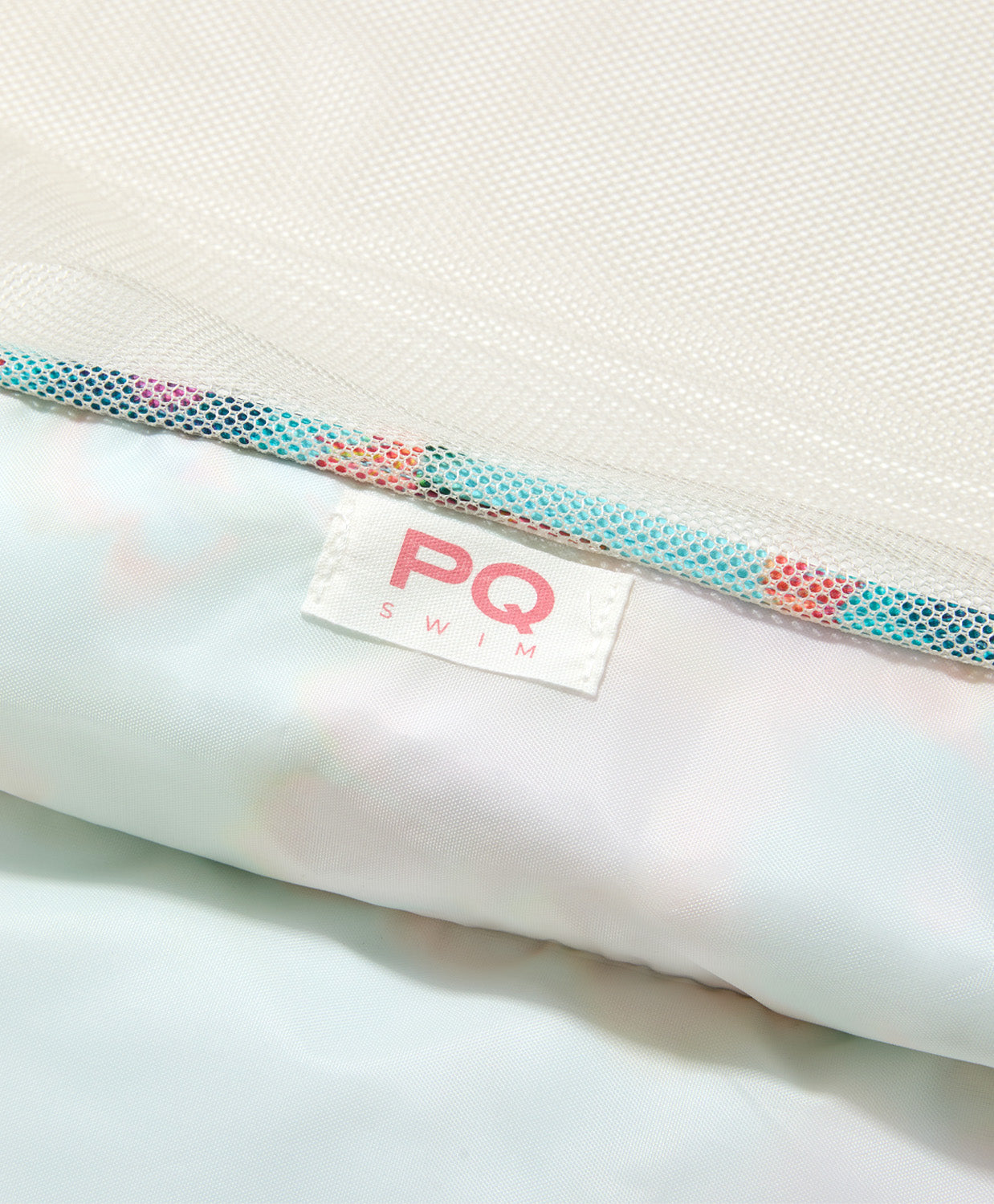 Close-up of a PQ Swim branded product with a textured strap on a white background