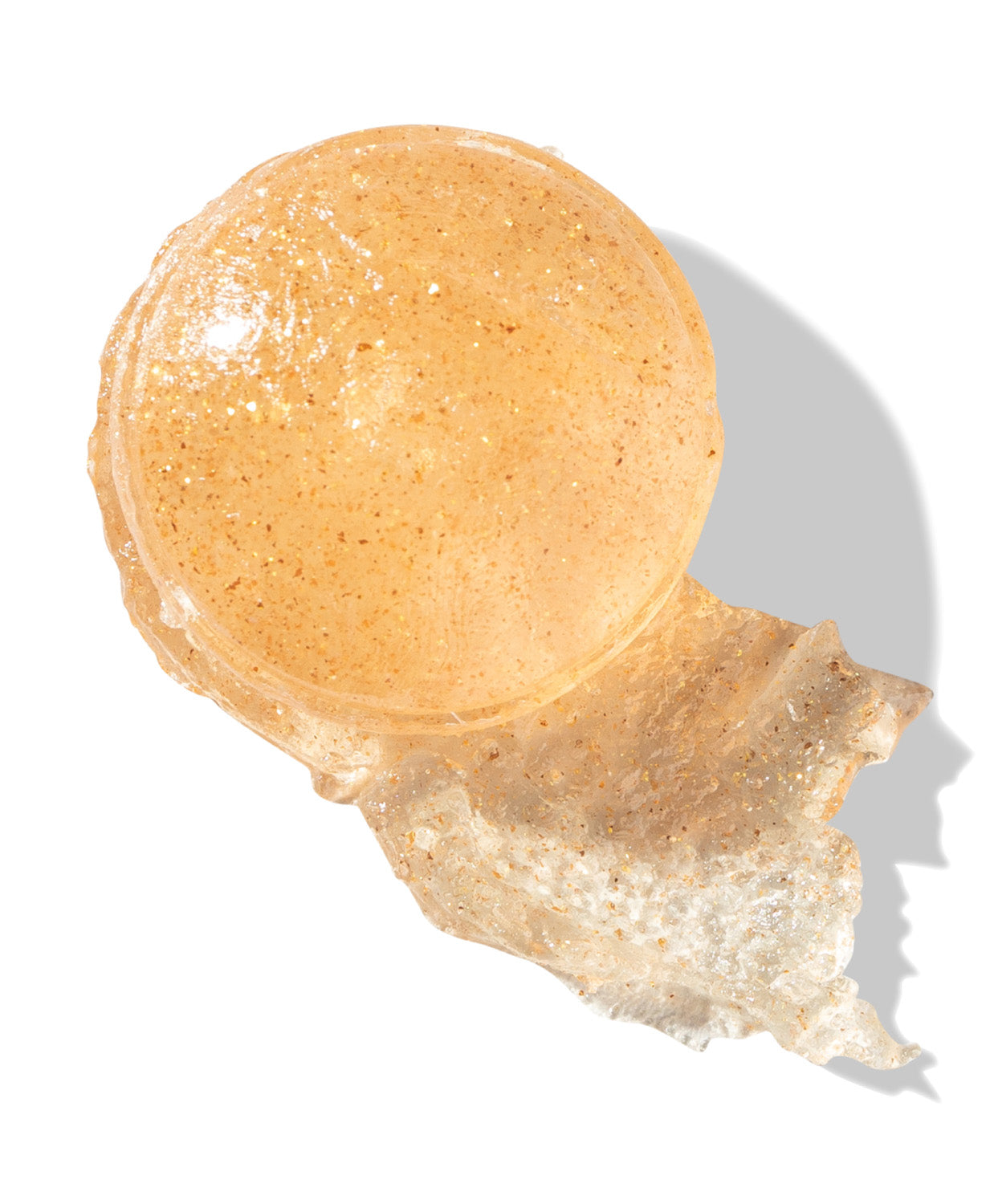 A close-up of the sheer stick product with a shimmery swatch smeared beside it.