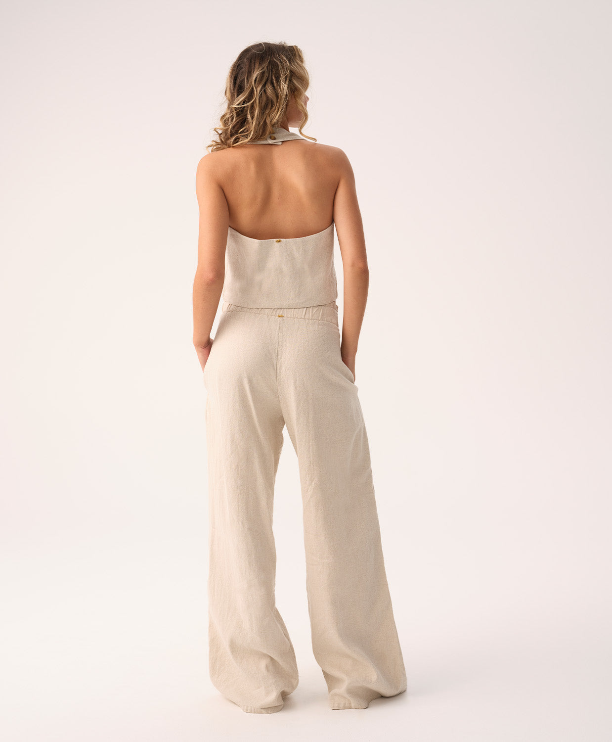 Woman wearing a beige strapless jumpsuit on a white background