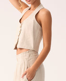 Woman wearing a beige sleeveless top and pants on a white background