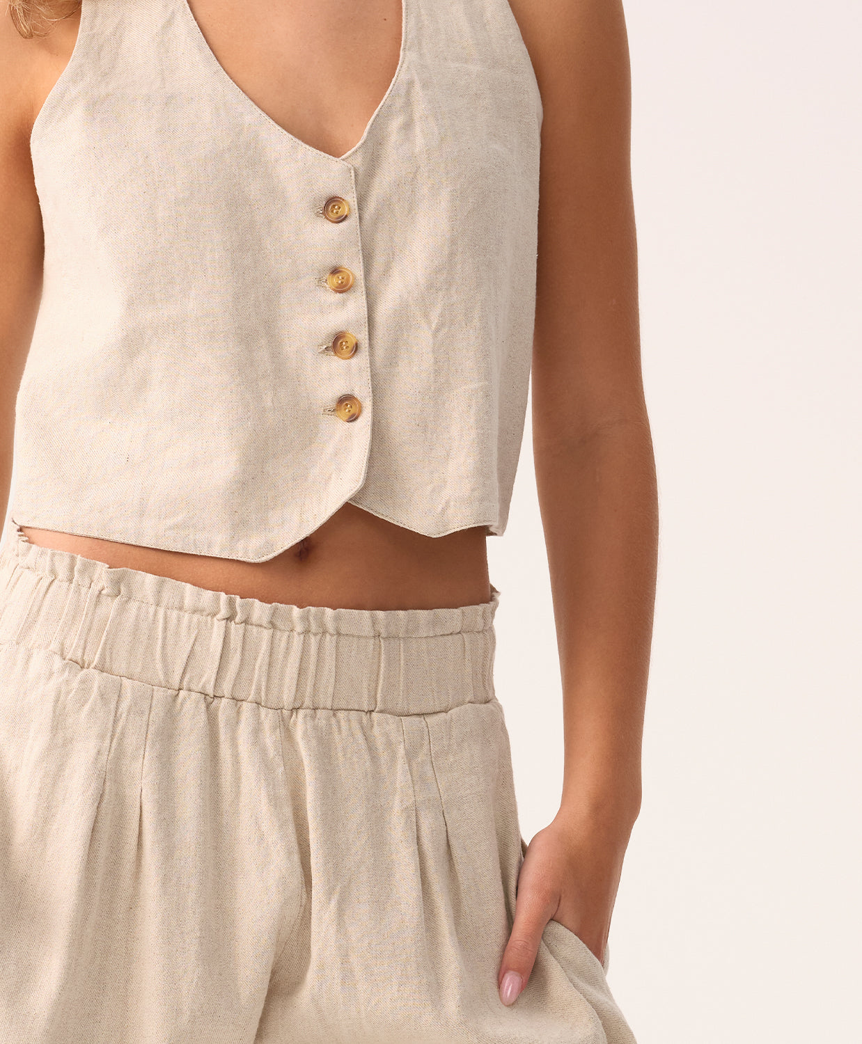 Beige sleeveless top with button details and matching pants on a neutral background