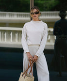 Woman in a beige outfit holding a straw bag outdoors
