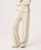 Woman wearing beige pants and top on a white background