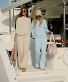 Two women in matching outfits walking down a yacht staircase.