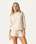 Woman wearing a beige hoodie and shorts on a white background