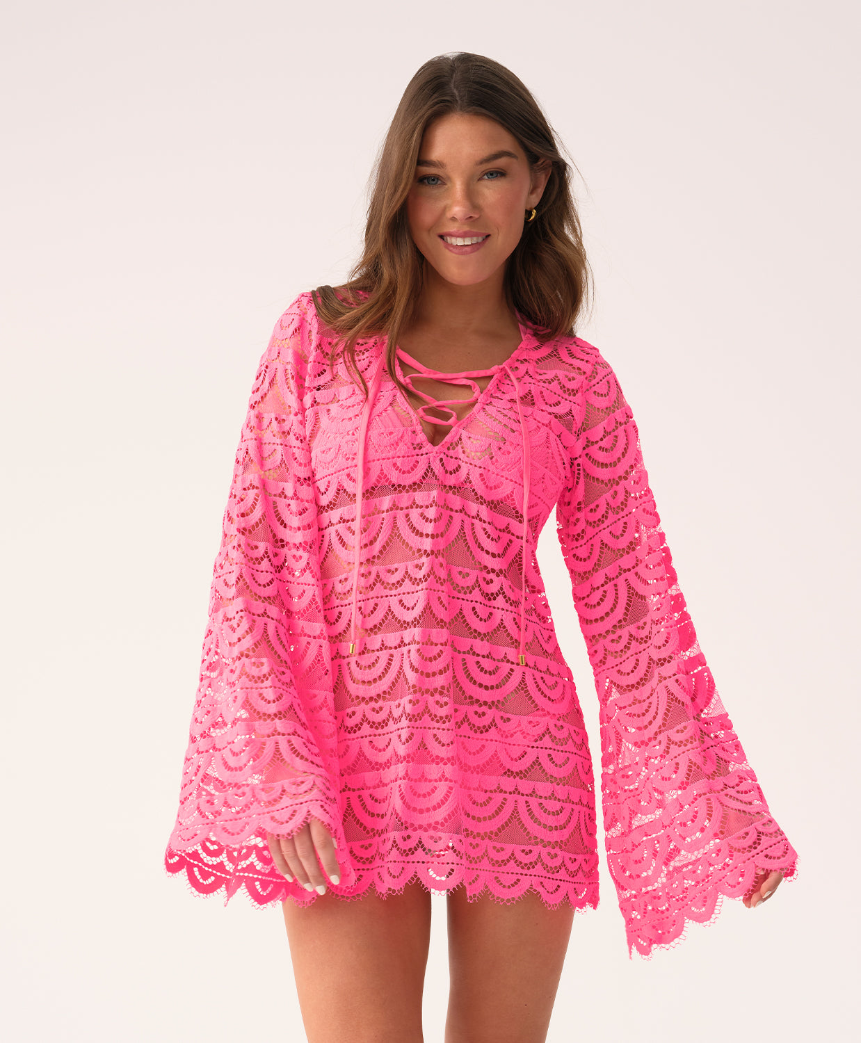 Woman wearing a bright pink lace dress on a white background