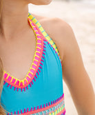 Close-up of a blue swimsuit with colorful trim on a blurred beach background
