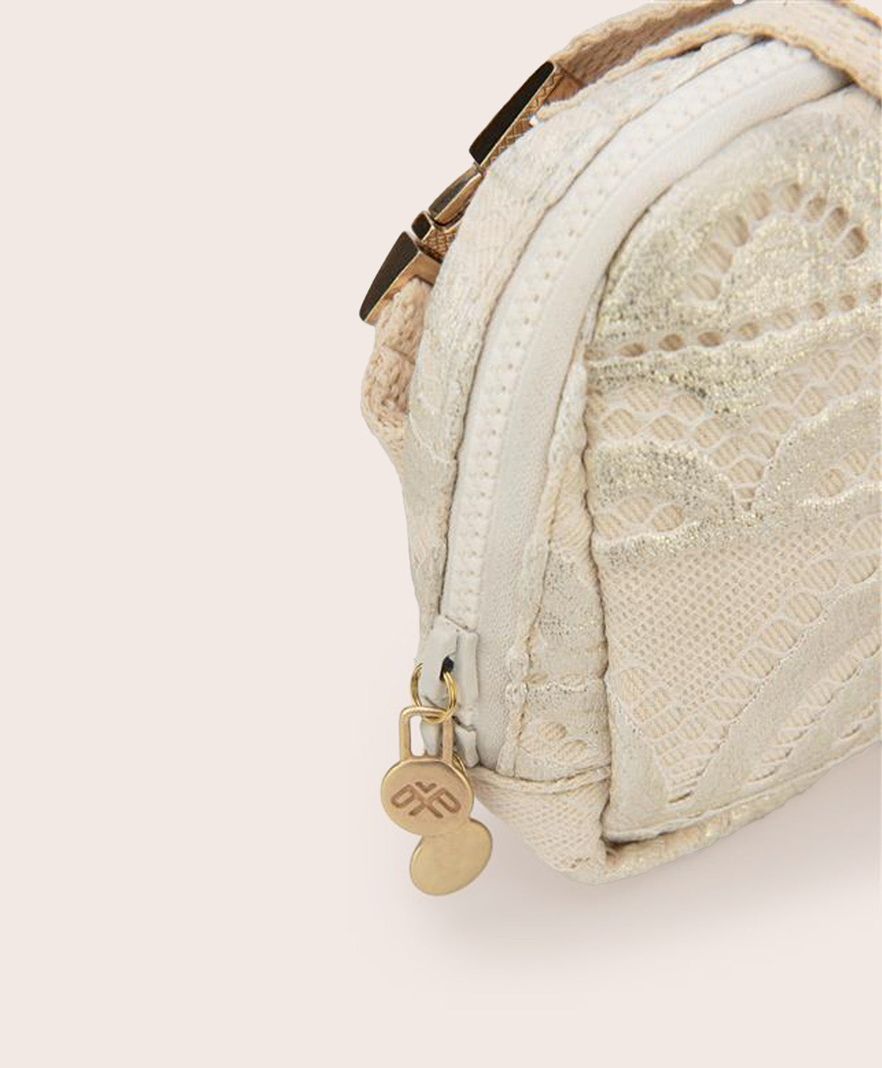 A tan colored lace crossbody bag against a white wall.