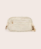 A tan colored lace crossbody bag against a white wall.