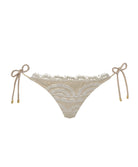 An ivory lace bikini bottom against a white wall. 