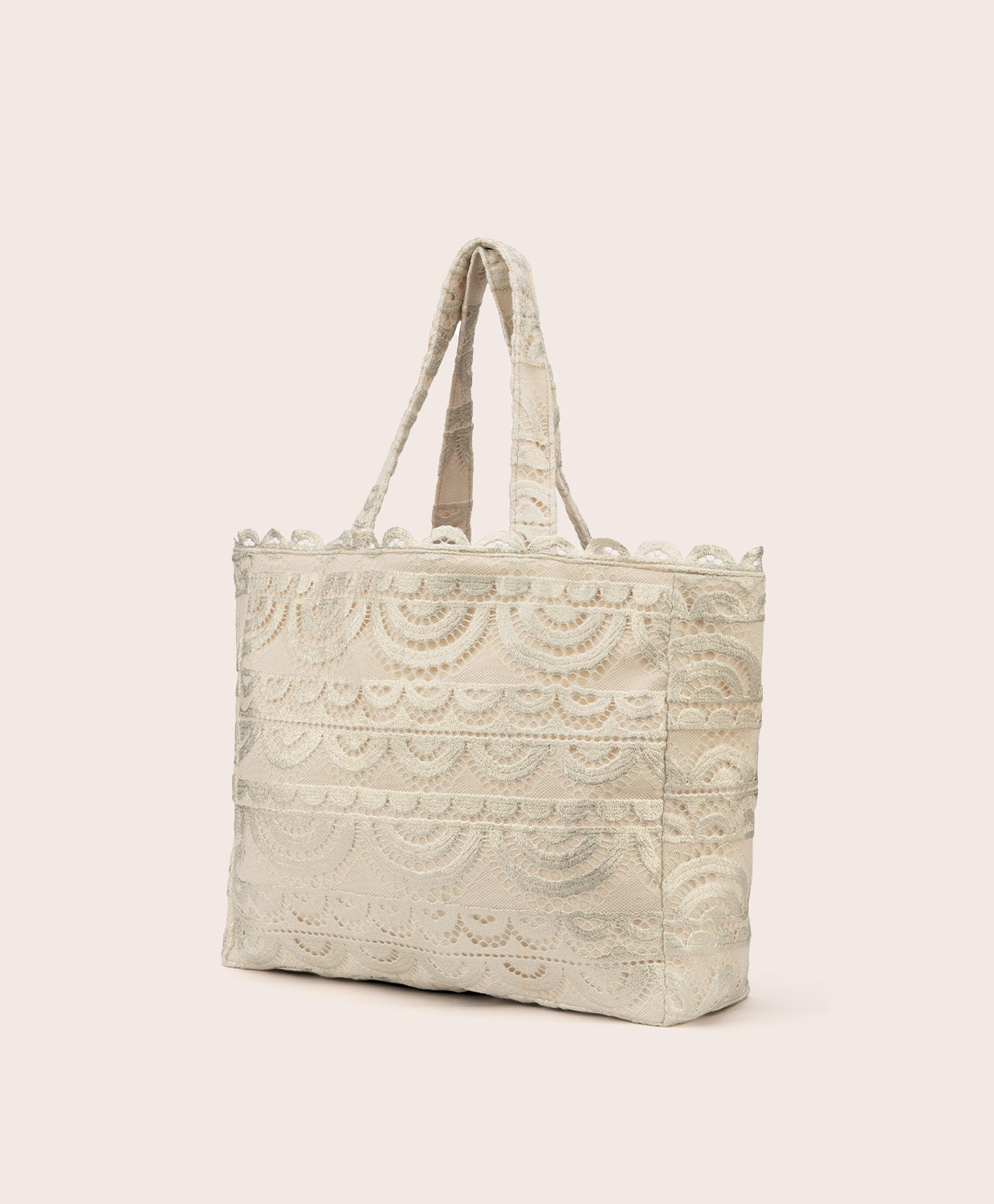 A tan lace tote with scalloped trim against a white wall. 