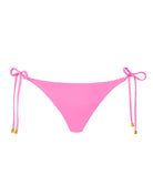A pink bikini bottom with tie sides against a white wall.